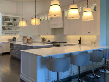 Contemporary kitchen with large island and hanging lights.