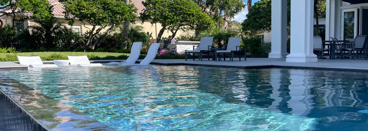 Close up of an infinity pool with lounge chairs floating in the shallow end.