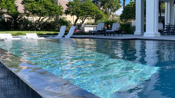 Outdoor pool with lounge chairs in the splash area of the shallow end.